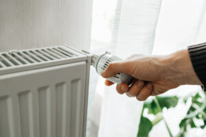 A man regulates the temperature on the radiator at home. Rising prices for heating in households. The concept of the energy crisis in Europe